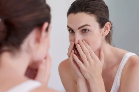 Woman looking at her skin in the mirror